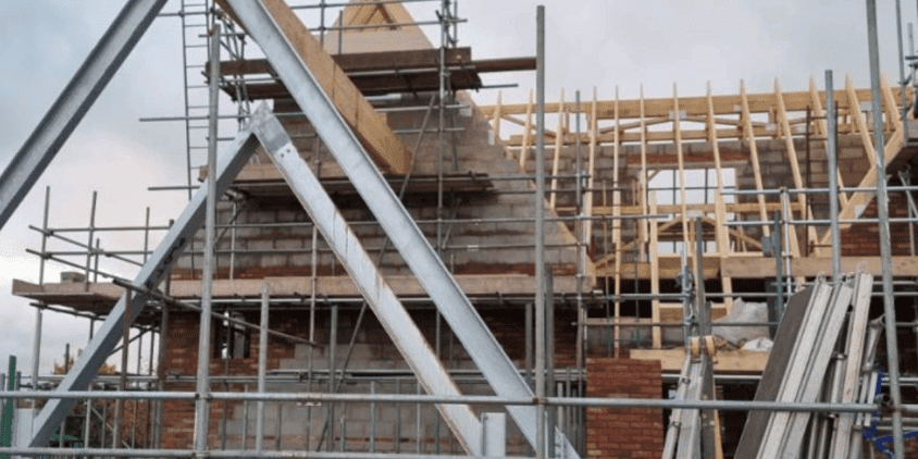 Construction site with scaffolding and subcontractor activity.